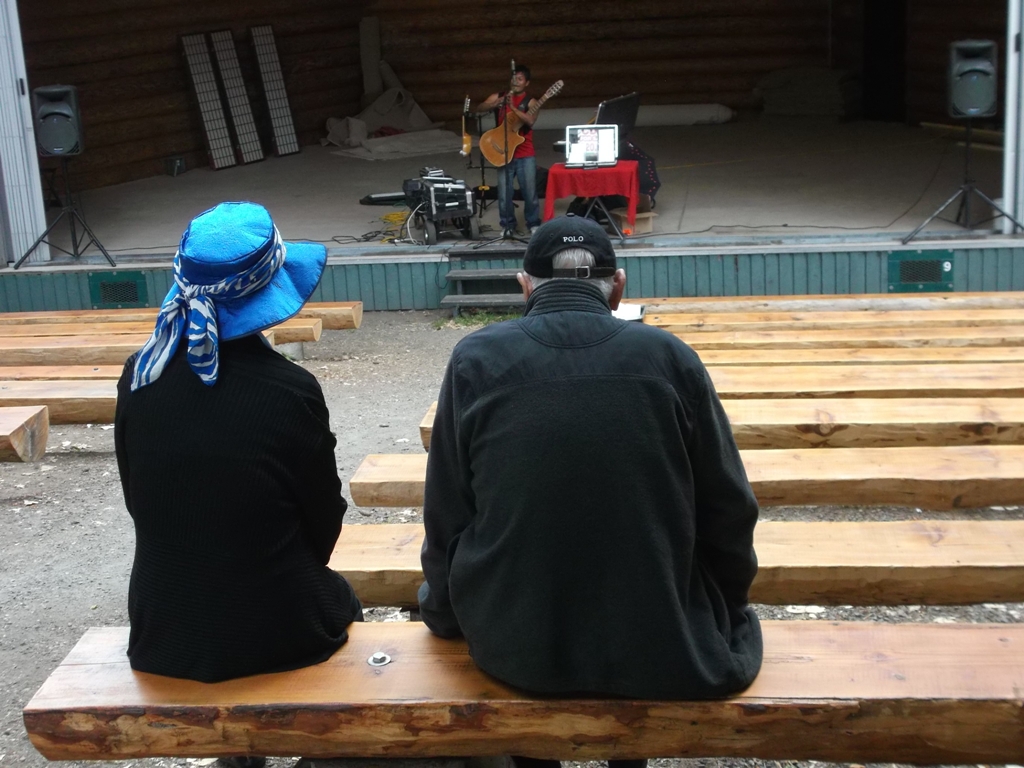 2012年8月6日，陈琼芳师母（左）与洛夫先生在Chemainus，欣赏流浪歌手的乐器表演。