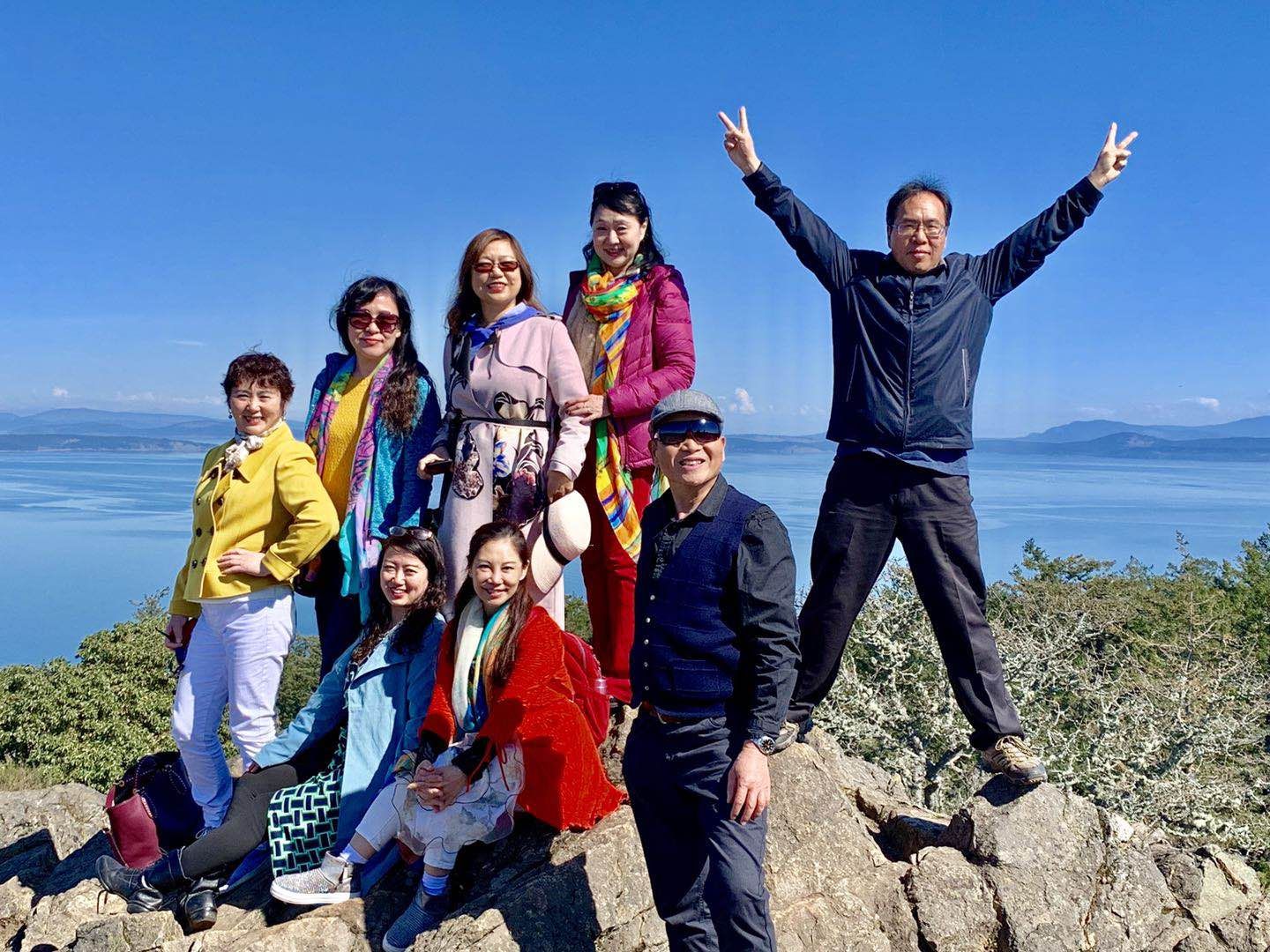 2019年3月30日正午，维多利亚市的制高点，道格拉斯山，高225米。背后是乔治亚海峡，远方是美国的奥林匹亚山脉，与高3286米的贝壳山雪峰。前排左起：竹笛，卫九如，沈家庄；后排左起：李影，冯玉，莫青，燕茹，和平岛。露头应该是辉长闪长质的片麻岩，与变质火山沉积岩。